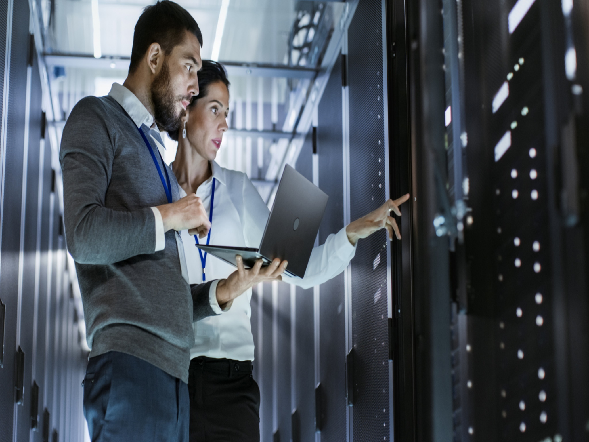 2 people looking at computer and server to solve IT issues