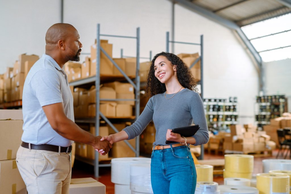 Manager meets with supplier to discuss supply chain details in a warehouse